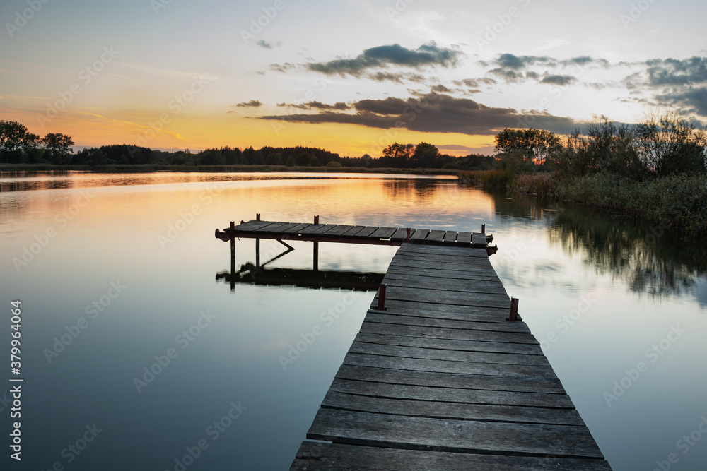 Wooden pier on a calm lake, view after sunset Wooden pier on a calm lake, view after sunset
