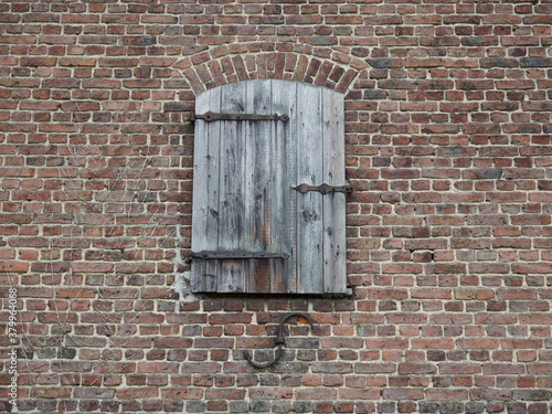 Photography An old little wooden door in the middle of a brick wall