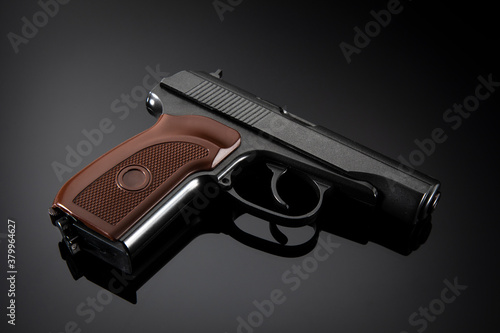 Black pistol with brown handle on gray gradient background