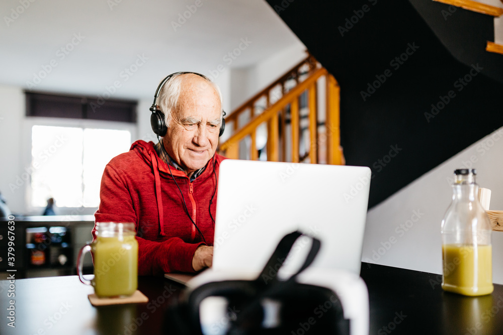 Smiling senior man in headphones using laptop. Smiling senior man in headphones using laptop.