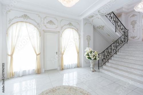 Fototapeta Naklejka Na Ścianę i Meble -  luxury royal posh interior in baroque style. very bright, light and white hall with expensive oldstyle furniture. chic wide marble staircase leading to the second floor