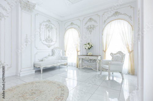 luxury royal posh interior in baroque style. very bright  light and white hall with expensive oldstyle furniture. large windows and stucco ornament decorations on the walls