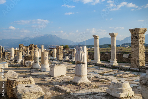 Side view onto empty colonnaded street in antique city Laodicea, near Denizli, Turkey. City included in Tentative List of UNESCO. Mountains are on background