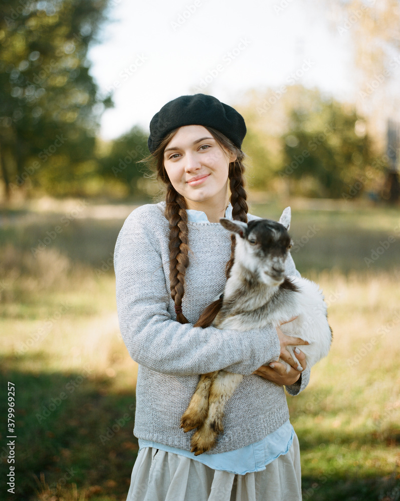 Happy woman holding small gray goatling Happy woman holding small gray goatling