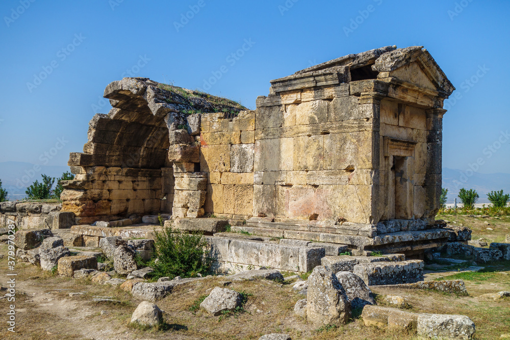 Antique crypt in necropolis of antique city Hierapolis, Pamukkale, Turkey. It was belonged to noble family. Entrance decorated with traditional portico, one of walls damaged. Roof overgrown with weeds