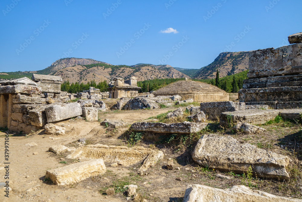 Antique crypts & remains of burial plates in necropolis in antique city Hierapolis, Pamukkale, Turkey. Central crypt built as tumulus. Some crypts have sarcophagus on roofs. City included in UNESCO