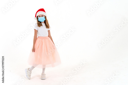 Adorable girl in a medical mask and santa claus hat on a white background. Snow Maiden.