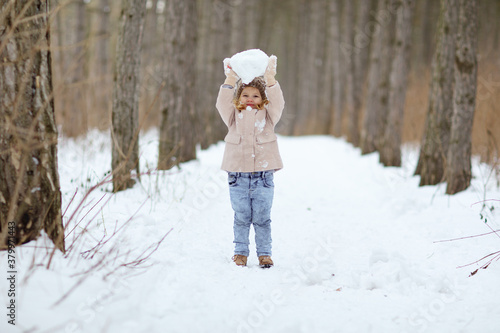 little girl play in the winter forest and make snow balls for the snowman. walking in any weather. new year vacations. happy childhood.