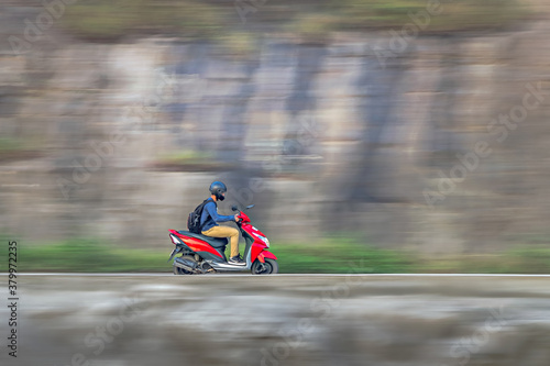 Motion blur image of a rider wearing helmet for safety, riding on two wheeler. photo