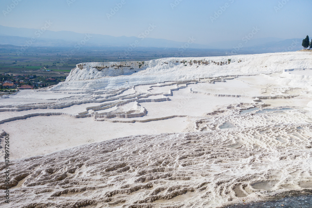 Panoramic view onto travertine terraces of Pamukkale, Turkey. Snow white color created by minerals containing in water flow