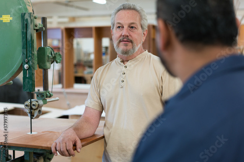 Caucasian man in factory listens to coworkers photo