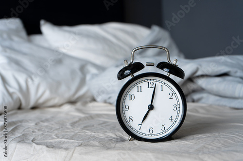 Stylish alarm clock with a bell. The hands show 7 hours. Wake up time