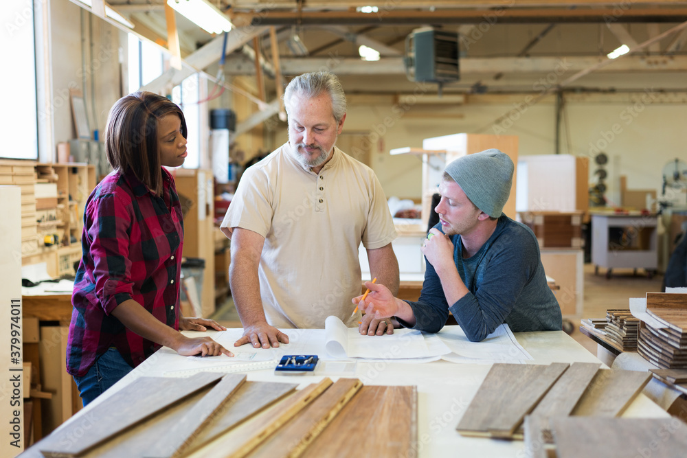 Horizontal of three blue collar workers talking over drawings in Horizontal of three blue collar workers talking over drawings in