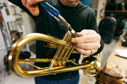 Band: Man Disassembles Trumpet In Workshop photo