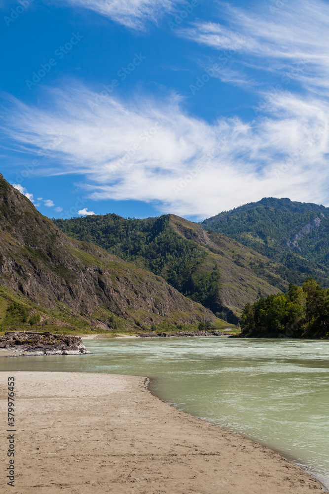 Fototapeta premium Summer day in mountainous Altai on the banks of the Katun river with turquoise water and mountain ranges covered with green forest. A secluded place to relax in Siberia.