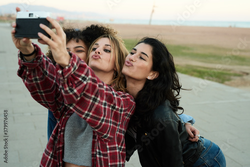 Pretty girls taking selfie via film camera.
