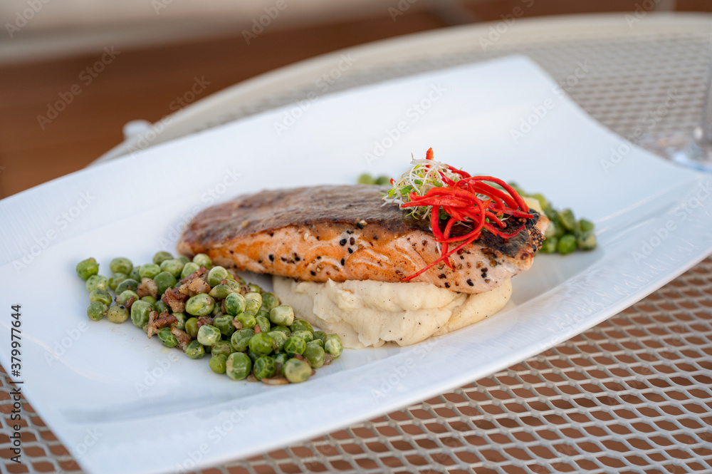 Grilled salmon with green peas, mashed potato in white plate on dining table Grilled salmon with green peas, mashed potato in white plate on dining table