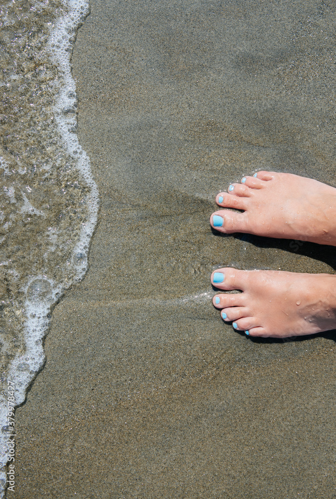 Woman's feet standing on a beach at the ocean's edge Woman's feet standing on a beach at the ocean's edge