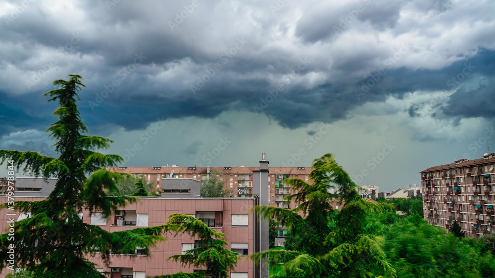 Heavy storm with dark clouds over residential buildings in Milan, Italy.