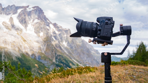 Camera on a gimbal filming. Mountains and clouds on the background. photo