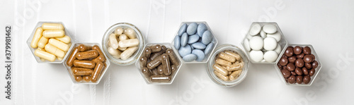 Various capsules and pills with dietary supplements or medicines in hexagonal jars photo