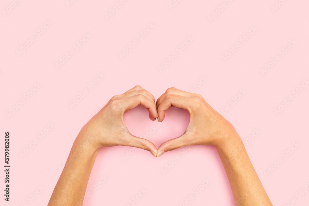 Manos de mujer haciendo una forma de corazón sobre fondo rosa pastel liso y aislado. Vista superior y de cerca. Copy space - obrazy, fototapety, plakaty 