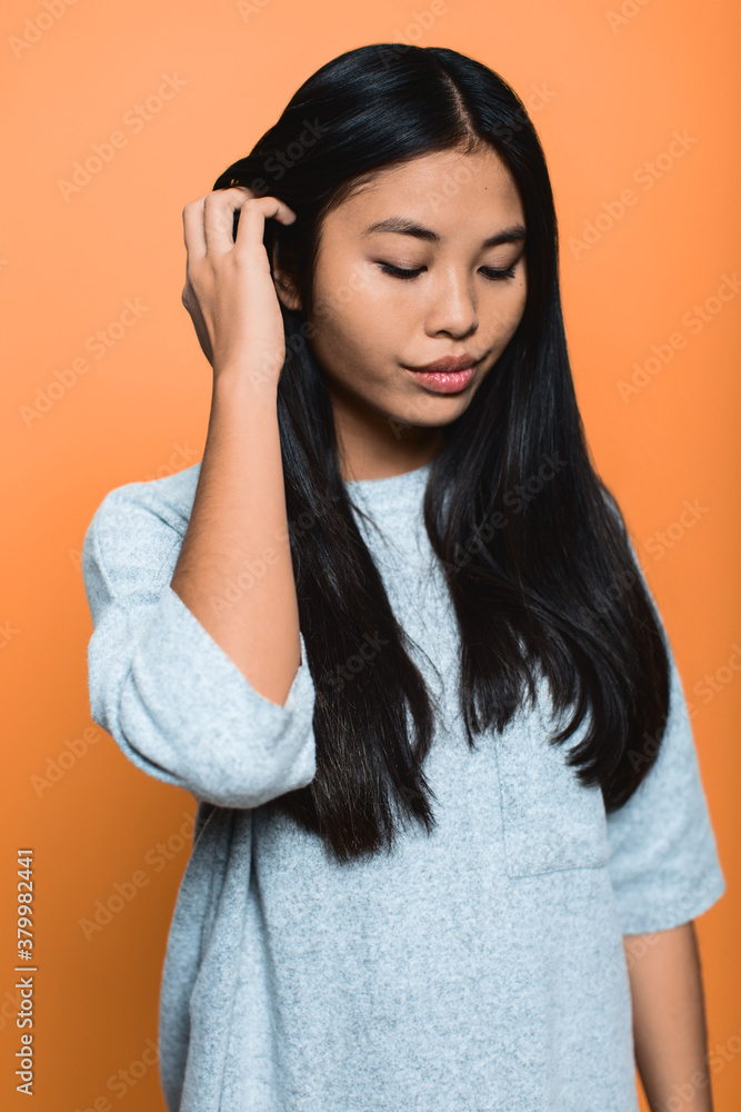 A pretty asian skater girl over orange background. A pretty asian skater girl over orange background.
