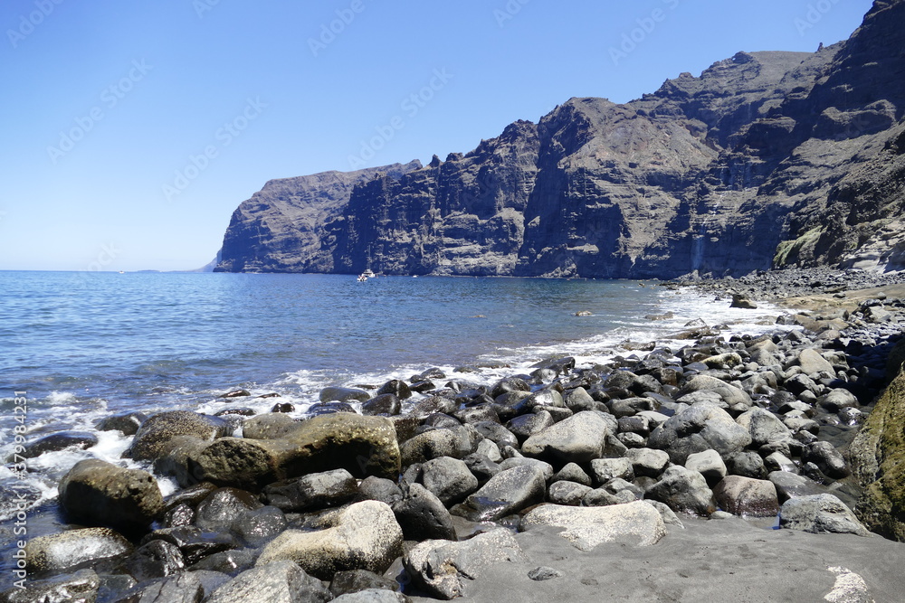 Rocky beach across Los Gigantes rocks  in Atlantic Ocean on Tenerife, Spain. 