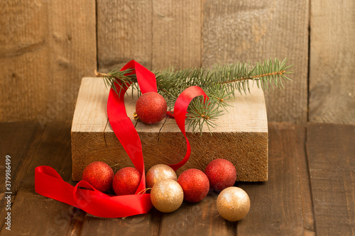 Christmas composition. Christmas tree branch, decor and red ribbon on a wooden background.