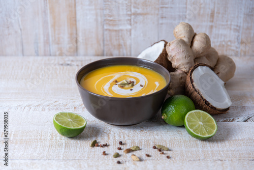 pumpkin cream soup in asian style with ginger and coconut milk on a white wooden table