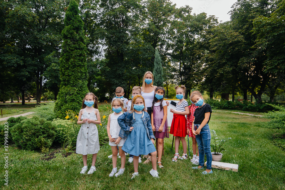 Obraz premium A class of masked school children is engaged in outdoor training during the epidemic. Back to school, learning during the pandemic