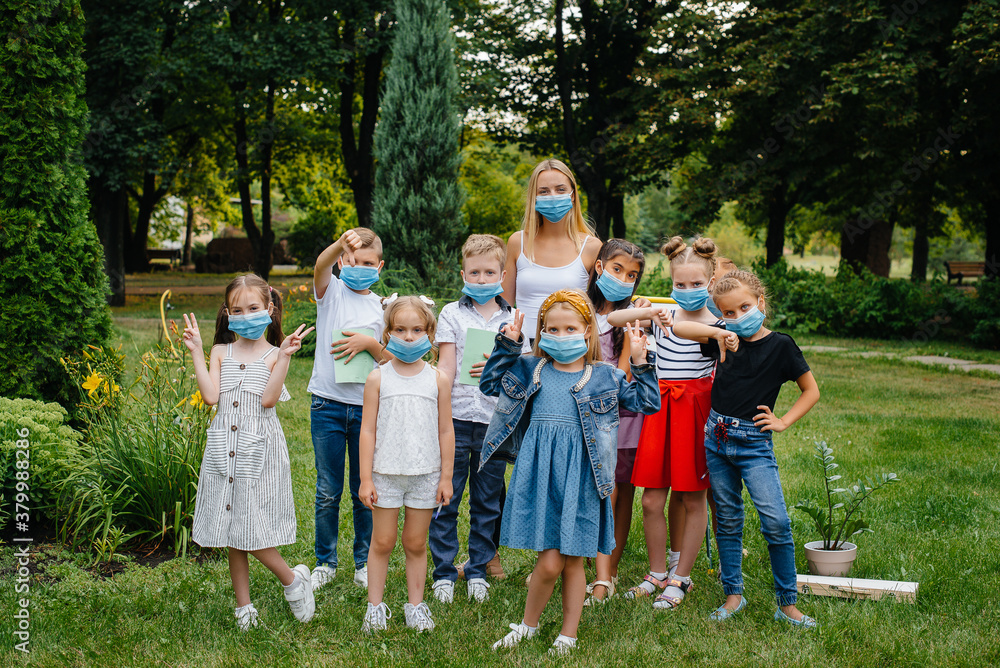 Fototapeta premium A class of masked school children is engaged in outdoor training during the epidemic. Back to school, learning during the pandemic