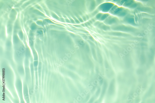 de-focused. Closeup of mint green transparent clear calm water surface texture with splashes and bubbles. Trendy abstract summer nature background. Mint colored waves in sunlight. Copy space. photo