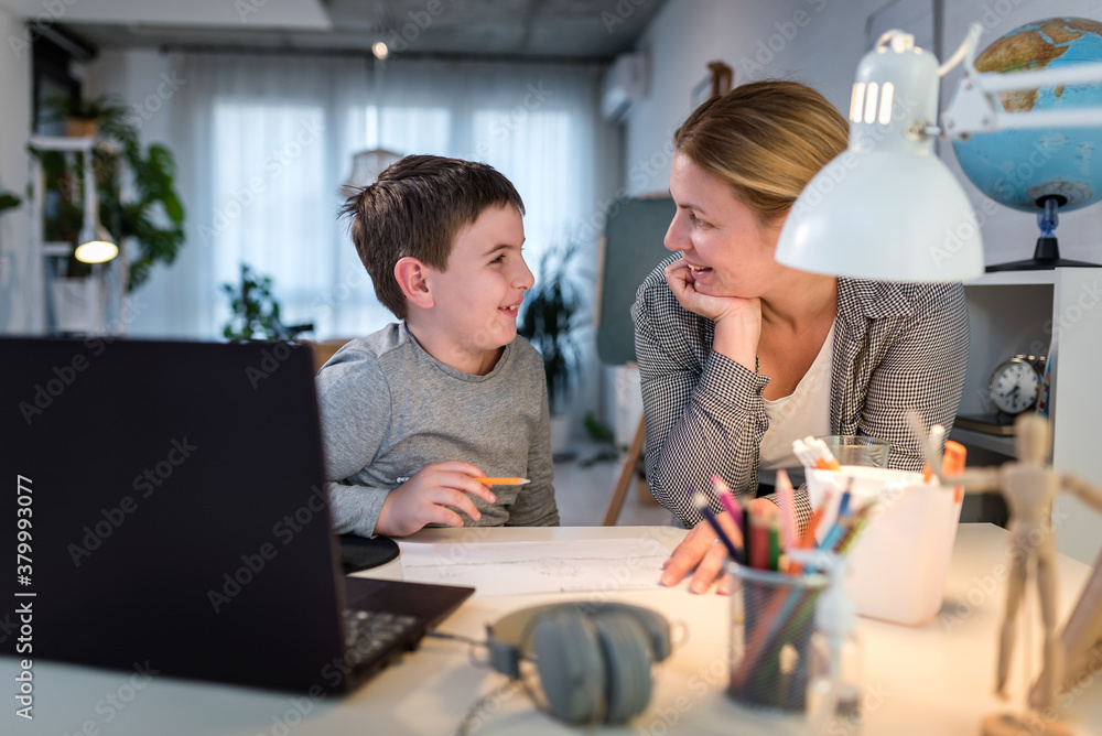 Mother helping child to do homework in front of laptop computer. Lifestyle concept of home schooling. Mother helping child to do homework in front of laptop computer. Lifestyle concept of home schooling.