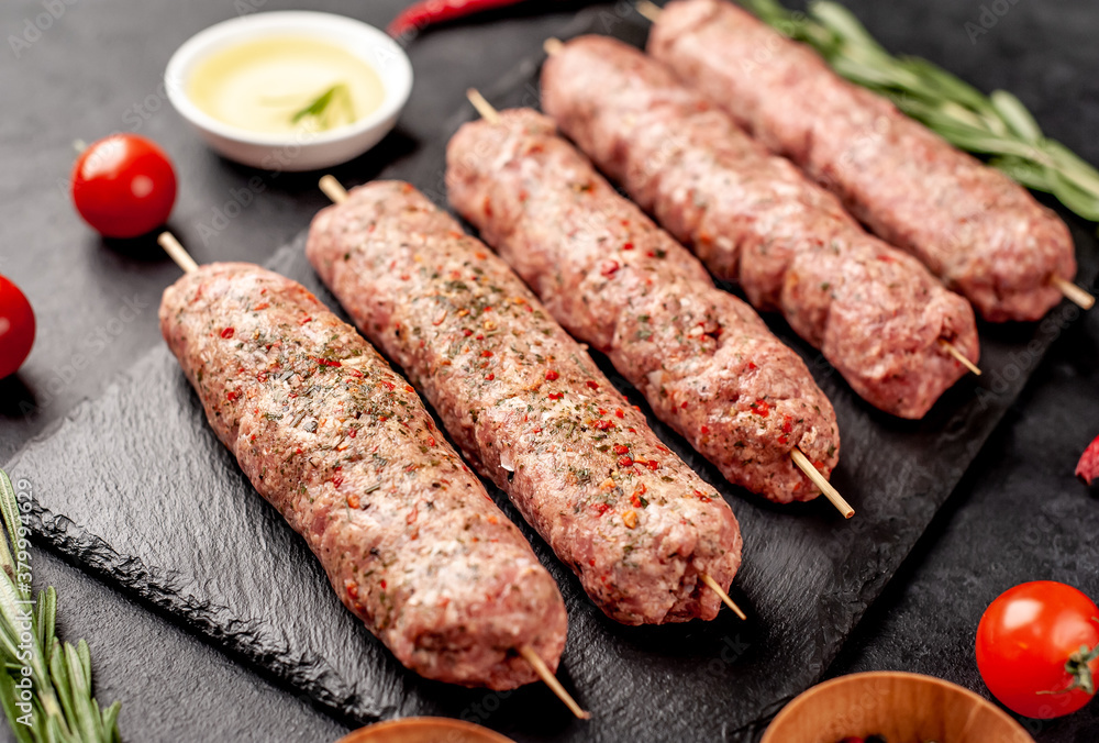 raw Lula kebab on skewers with spices on a stone background raw Lula kebab on skewers with spices on a stone background