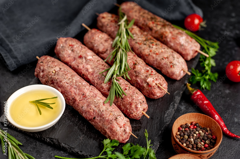 raw Lula kebab on skewers with spices on a stone background raw Lula kebab on skewers with spices on a stone background