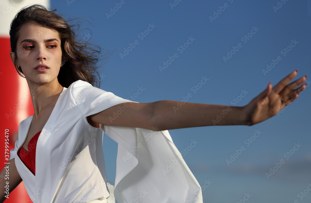 Beautiful girl in white clothes on a blue sky background Beautiful girl in white clothes on a blue sky background