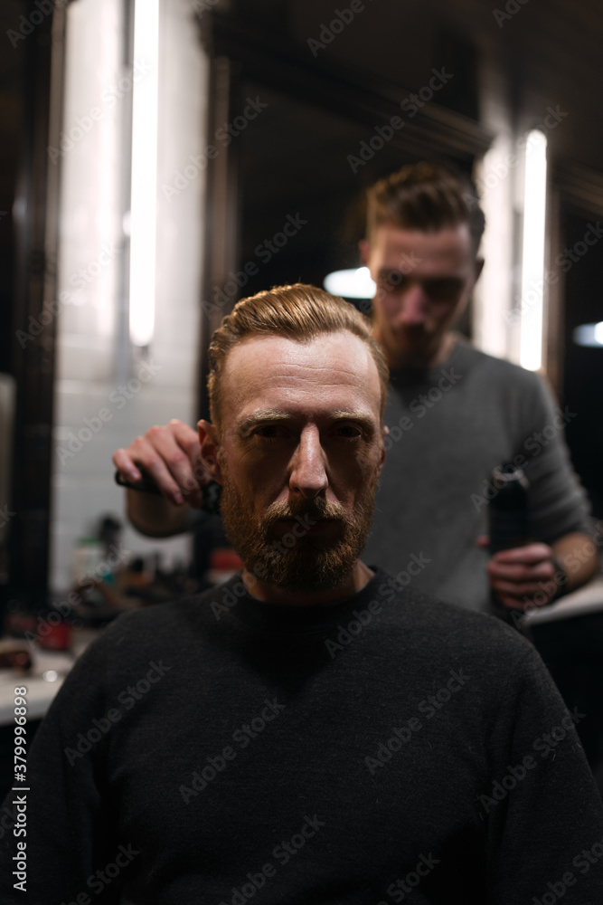 Serious customer while having a haircut at barbershop Serious customer while having a haircut at barbershop