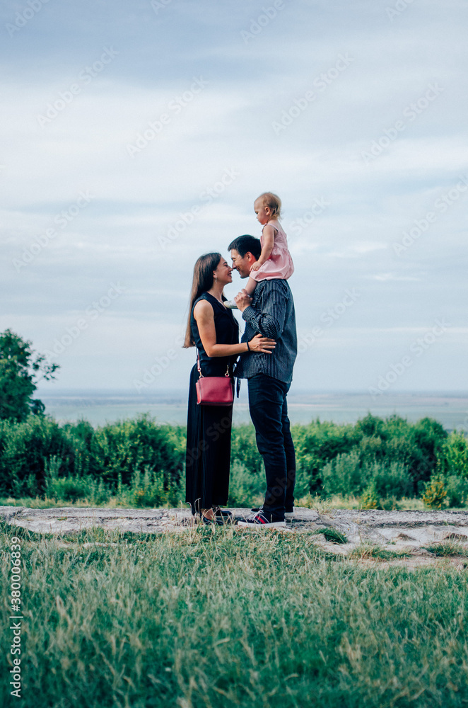 Mother and father with daughter on his neck looking at each other Mother and father with daughter on his neck looking at each other