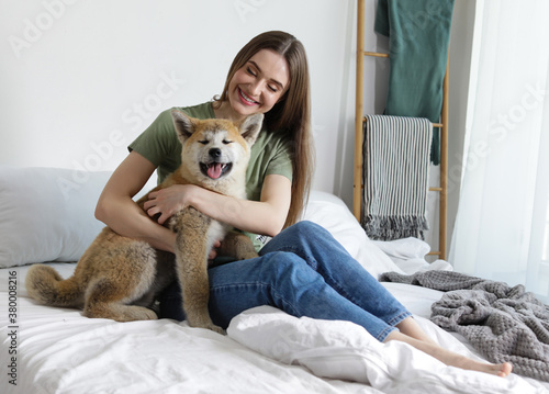 Happy woman with her cute Akita Inu puppy at home