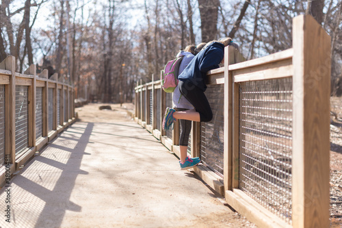 Two Young Girls Look Over A Bridge At The Creek Below