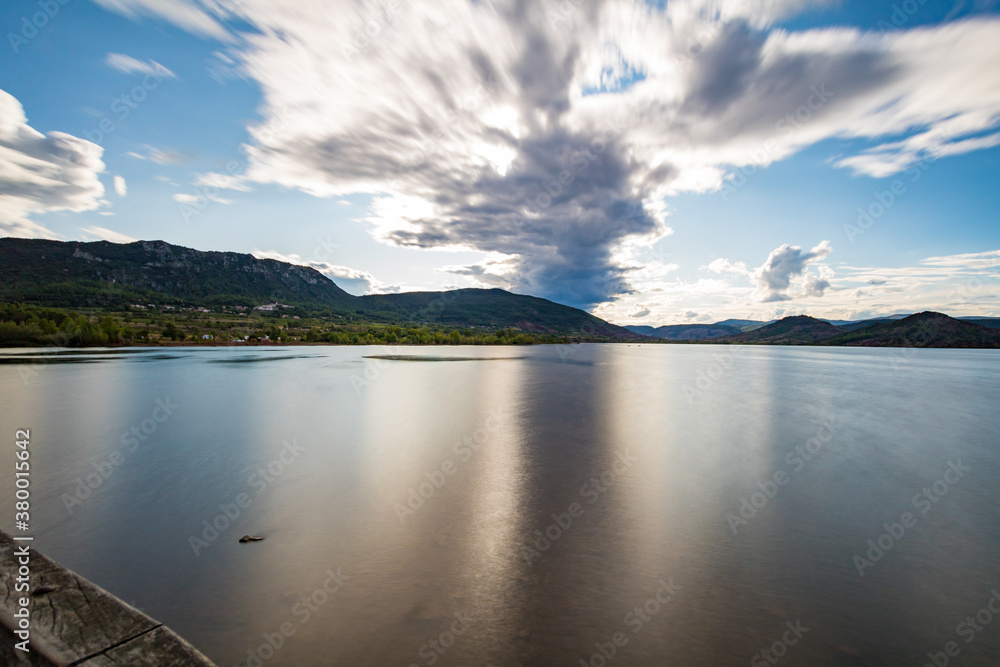 Vue en longue exposition sur le lac du Salagou par temps nuageux (Occitanie, France)