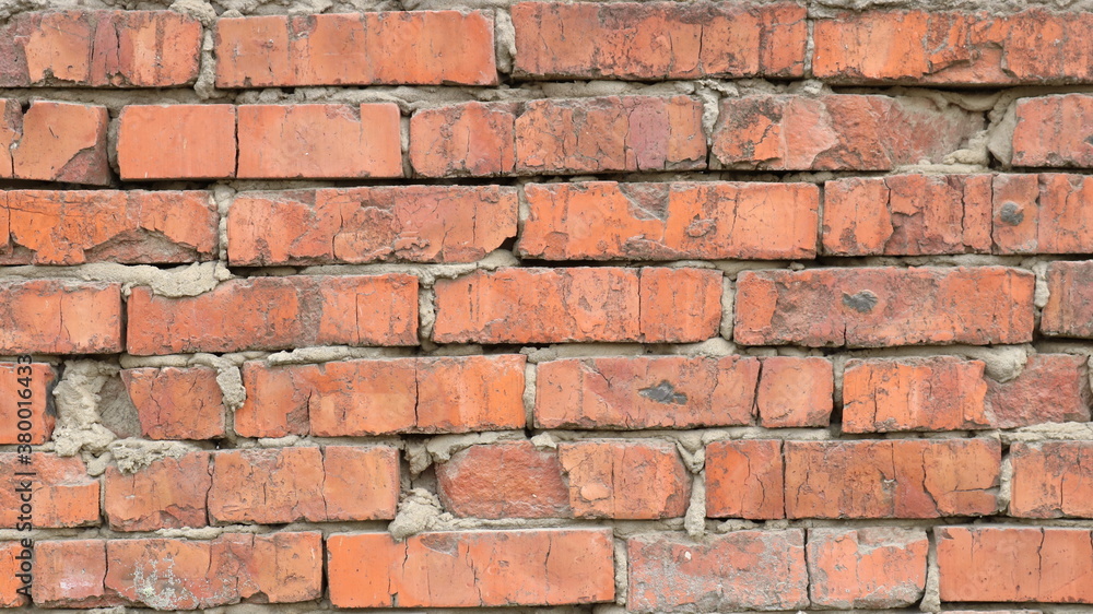 fragment of a dilapidated brick wall with a rough texture of old broken blocks and uneven layers of gray dried concrete mortar fragment of a dilapidated brick wall with a rough texture of old broken blocks and uneven layers of gray dried concrete mortar