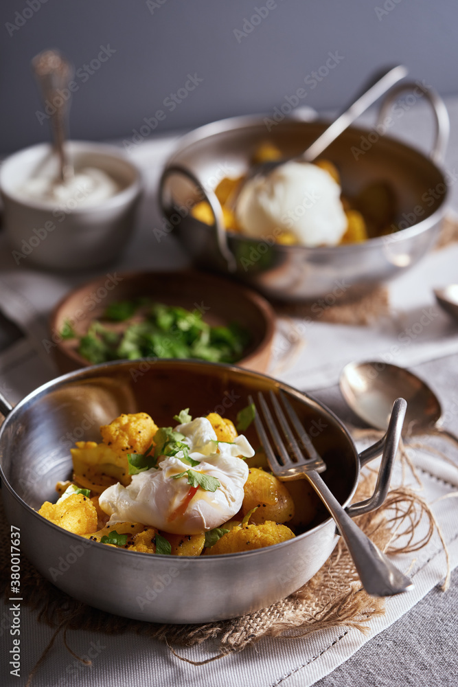 Aloo gobi with poached eggs on a table for breakfast. Aloo gobi with poached eggs on a table for breakfast.