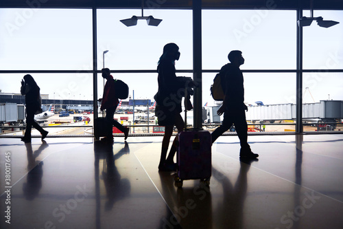 Silhouettes of air travelers navigating the terminal to board airplane flights amid pandemic. photo