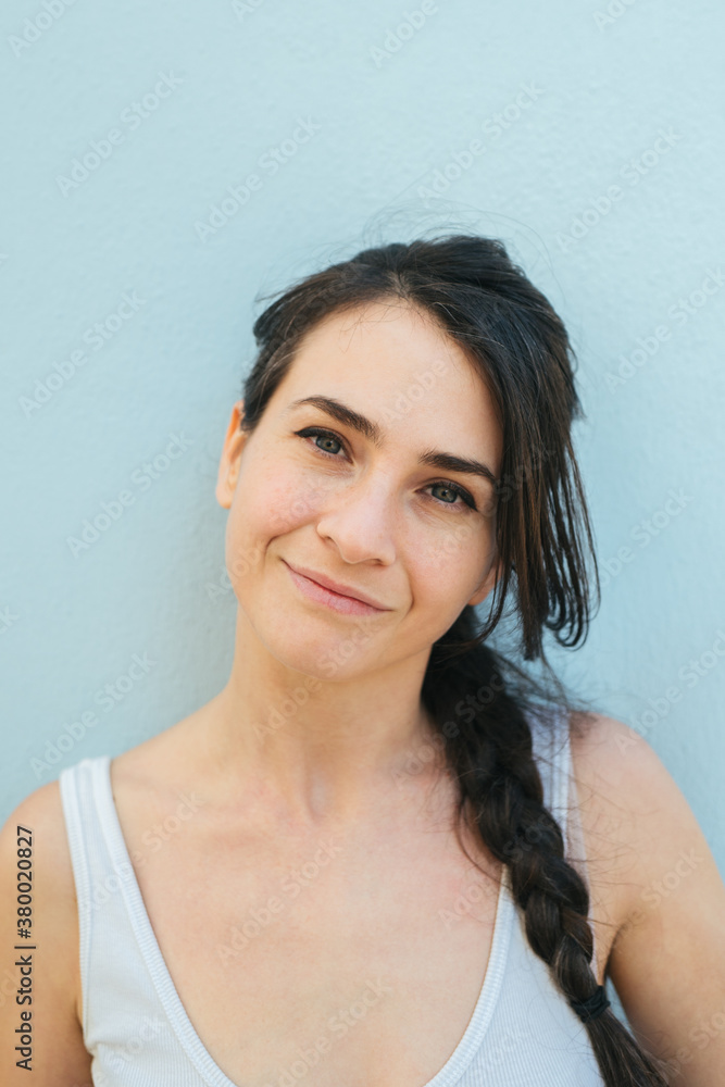 Portrait of a brunette woman with a braid against a Pale Blue background Portrait of a brunette woman with a braid against a Pale Blue background