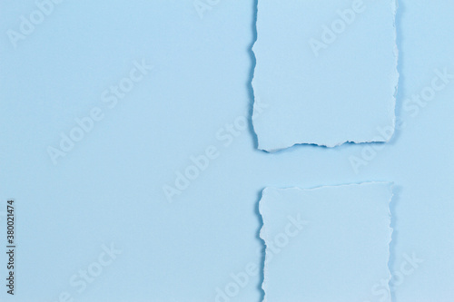 Abstract monochrome background. Pieces of torn paper on light blue background. Top view