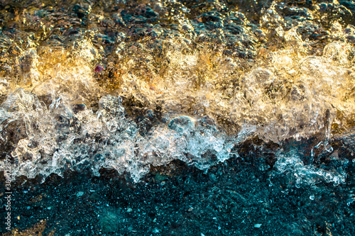 Top down view of breaking waves tinged by the setting sun photo