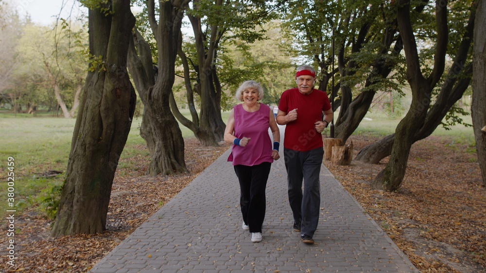 Obraz premium Active senior elderly couple doing cardio morning exercise workout. Man, woman running in city park.
