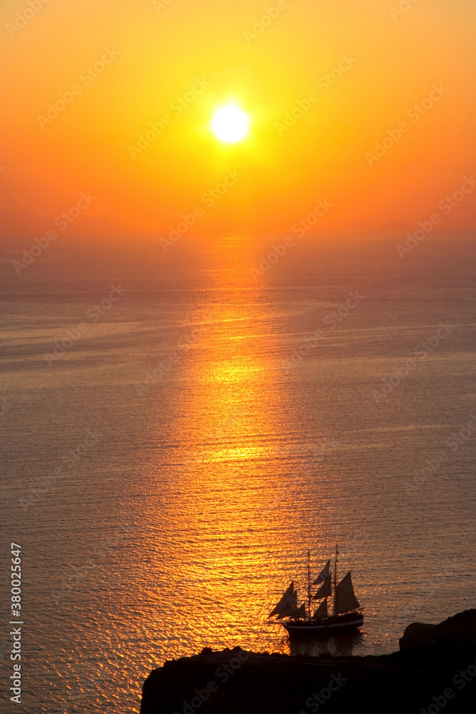 Magnificent sunset on Santorini in Greece. A ship with sails sails across the sea in the sunset. Magnificent sunset on Santorini in Greece. A ship with sails sails across the sea in the sunset.
